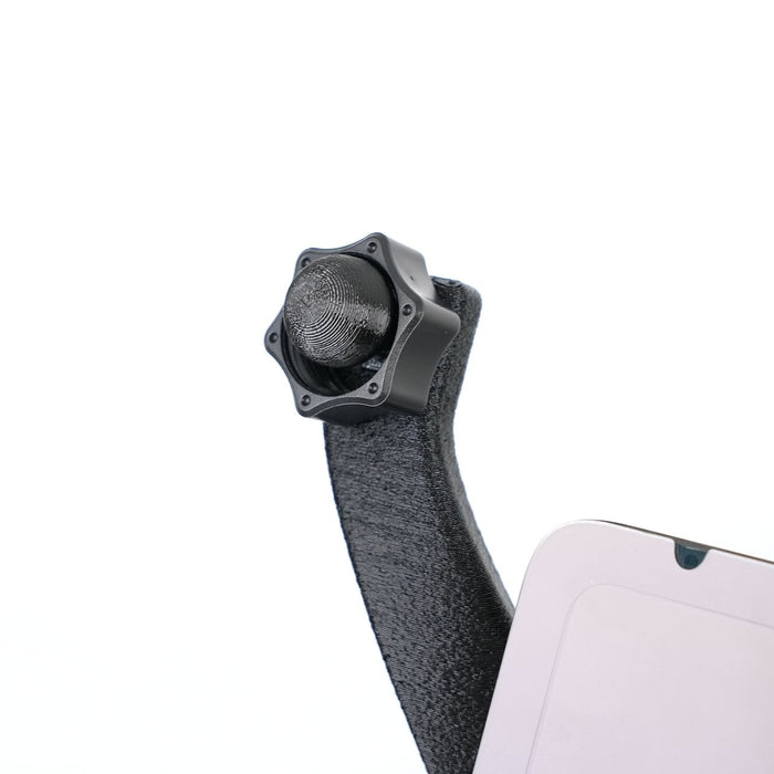 Close-up of a black knob attached to a textured arm, next to a partially visible rectangular device.