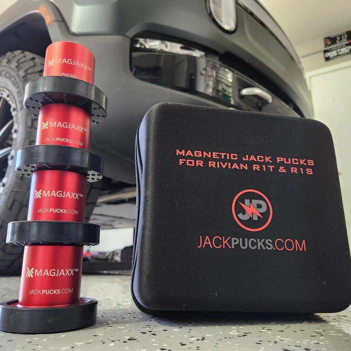 In the garage, a set of Jack Pucks No. 1 Selling Rivian Magnetic Jack Puck Kit to Change or Rotate Tires sits neatly beside a branded case, with the robust frame of a Rivian R1T subtly visible in the background.