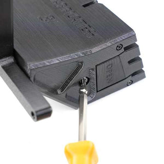 A screwdriver with a yellow handle is inserted into a black plastic 3D printer component labeled CREALITY.