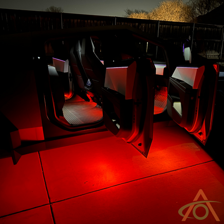 An open car door at night reveals a glowing red interior from lighting upgrades and a luminous concrete surface. Ultrabright Lights by Abstract Ocean for Cybertruck cast a unique glow, with a wooden fence in the background.