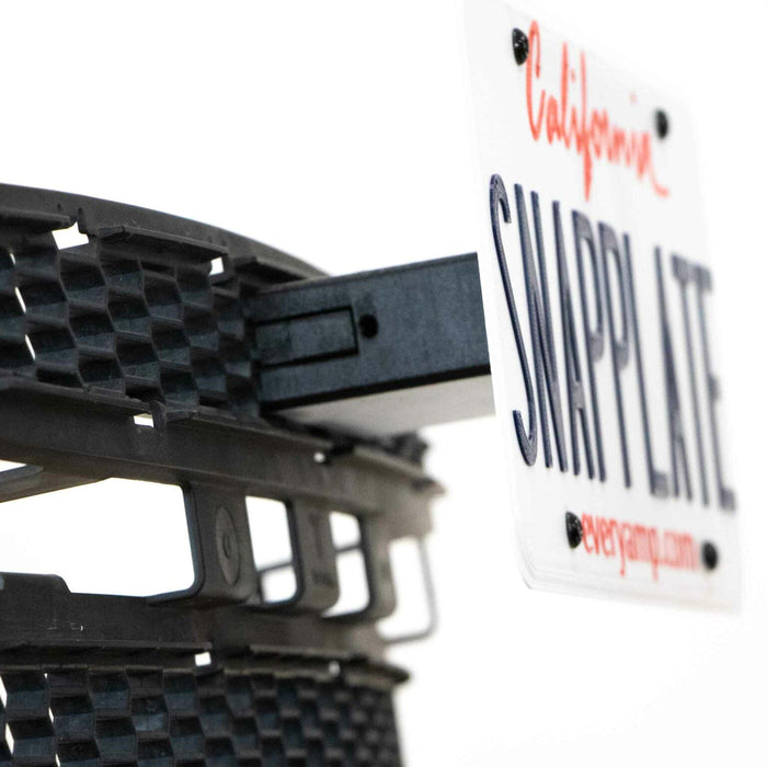 A close-up of a SNAPPLATE license plate holder attached to a vehicle bumper, featuring a white California license plate with red and black text.