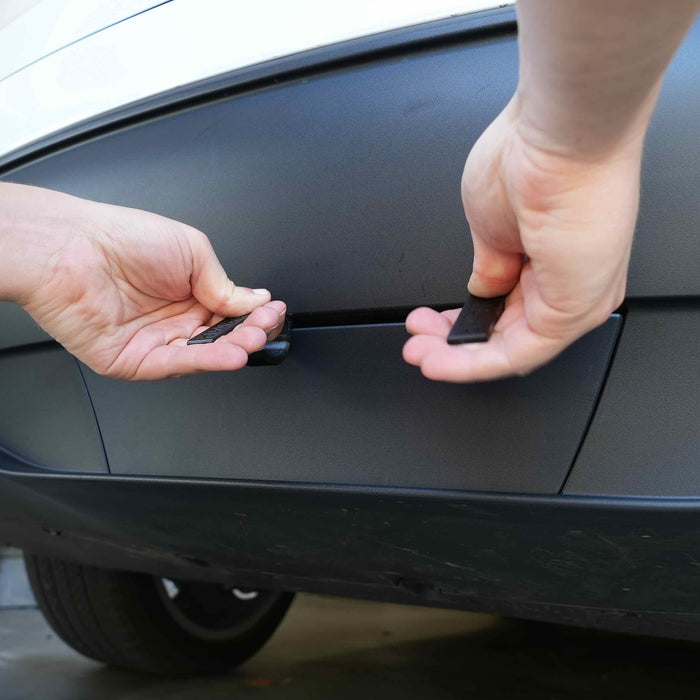 Hands removing plastic covers from the bumper of a car in a close-up shot.