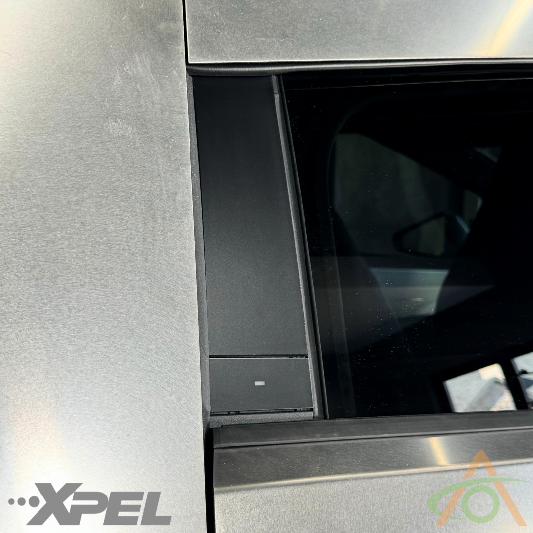 Close-up of a car window with matte black finish showing Abstract Ocean logo and another logo on B-Pillars, featuring top-notch PPF for Cybertruck - B & C Pillar Protection.