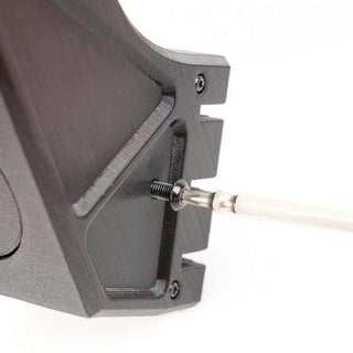 A screwdriver is inserting a screw into a black metal bracket.