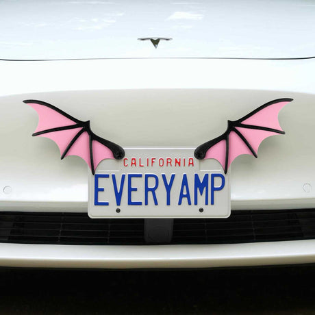 A white car displays a front SnapPlate featuring EveryAmp, adorned with License Plate Bat Wings in pink, made from recycled PETG plastic on each side.