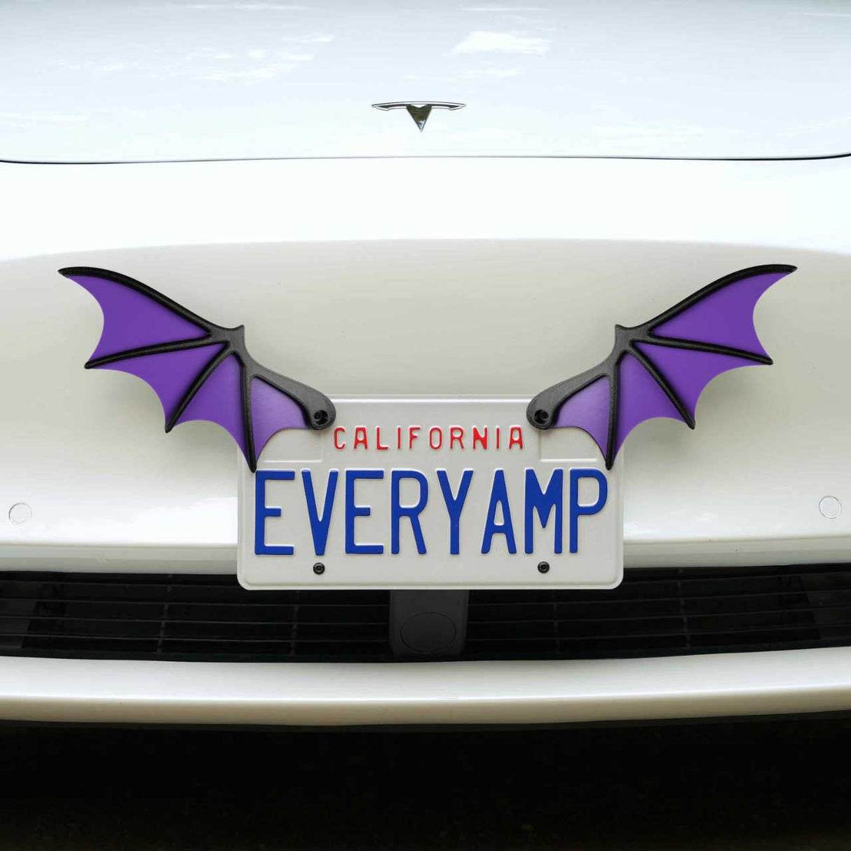 A white car with a California license plate EVERYAMP features two License Plate Bat Wings by EveryAmp, in purple, crafted from recycled PETG plastic for an eco-friendly touch.