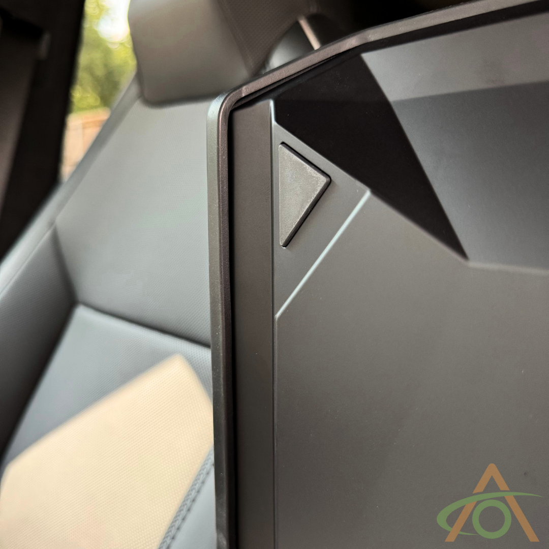 Close-up of a car interior displaying a geometric-shaped door panel with a triangle button. The Abstract Ocean Protective Armrest Cover for Cybertruck enhances the sleek lines, and part of the car seat is visible in gray and beige tones.