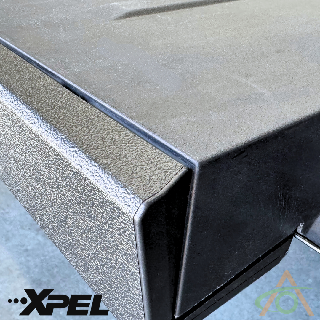 Textured protective covering featuring the Abstract Ocean logo in the bottom left and colored logo in the bottom right. This robust Ultra-Tough Xpel Armor Bed Protection by Abstract Ocean offers ultimate durability for your Cybertruck.