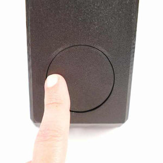 A finger pressing a circular button on a black rectangular device against a white background.