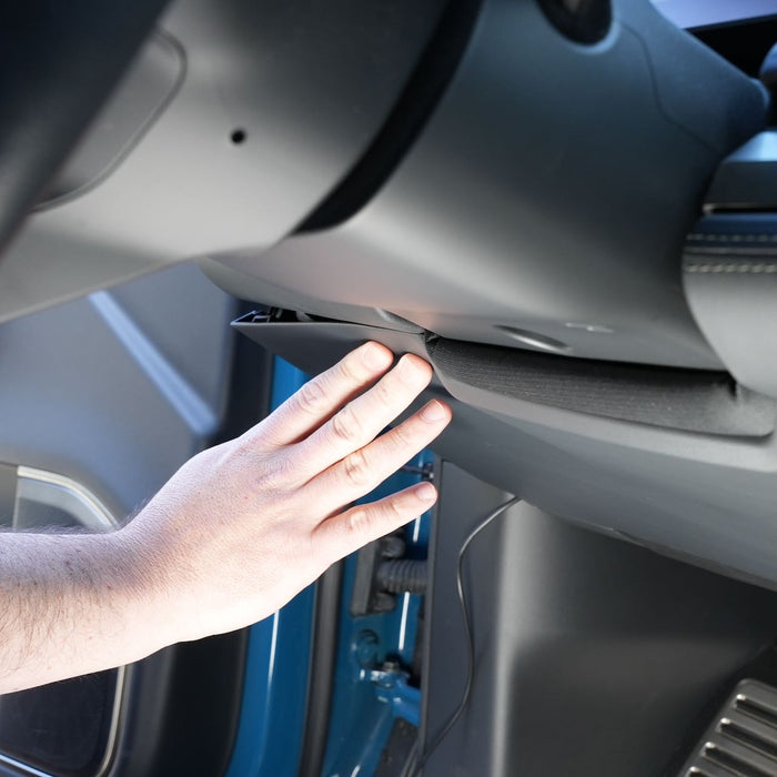 A persons hand reaching to open the glove compartment in a vehicles dashboard.