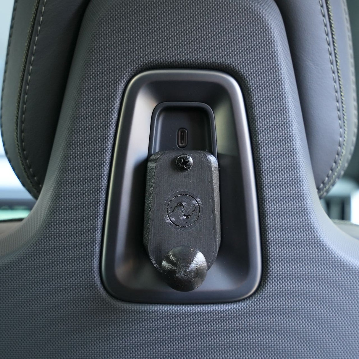 Close-up of the EveryAmp Back Seat Tablet/Phone Mount Anchor for Rivian R1T and R1S attached to a car seat, highlighting textured upholstery and stitching—a practical accessory for added versatility.