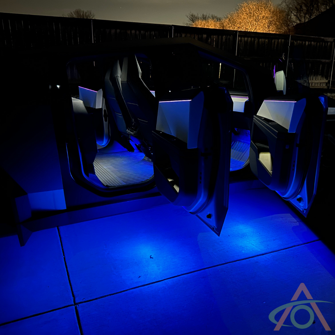 Cybertruck interior illuminated by Abstract Oceans Ultrabright Lights, featuring a futuristic design with open scissor doors, glowing blue at night.