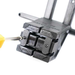 Close-up of a screwdriver tightening a screw on a black 3D-printed plastic part with multiple interlocking components.
