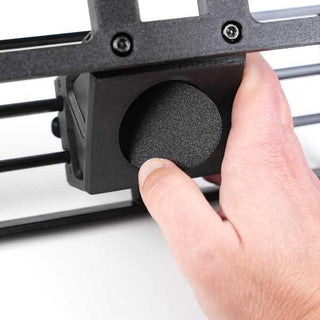 A hand adjusting a round black knob on a metal frame with visible screws.