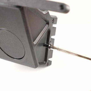 Close-up of a black 3D-printed object with a hexagonal opening, featuring a metal rod inserted through a round hole on the side.