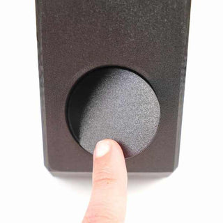 A finger pressing a circular button on a dark rectangular electronic device.