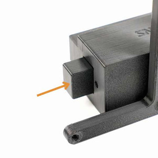Close-up of a black 3D-printed object with an arrow pointing to a square protrusion on the side.
