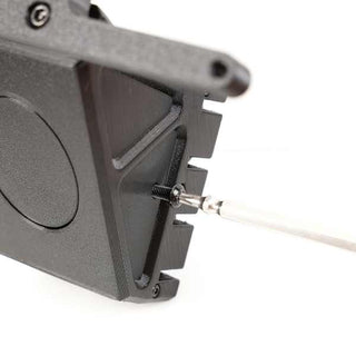 Close-up of a black rectangular device with a circular indentation and a metal rod connected to it via a screw.