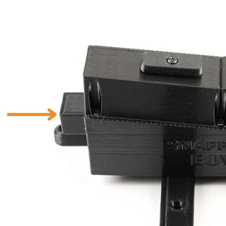 Black mechanical component with a side lever indicated by an orange arrow. Other parts include a top screw and visible grooves for attachment.