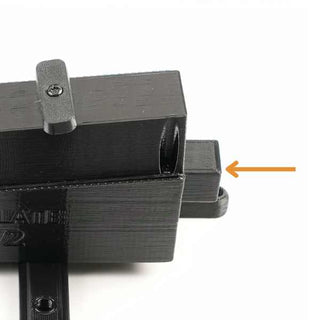 A black 3D-printed component with a protruding rectangular piece highlighted by an orange arrow.