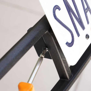 A screwdriver is tightening a screw on a metal frame attached to a sign.