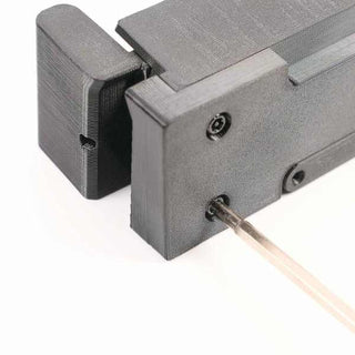 A close-up of a black rectangular mechanical device with a metal rod inserted into a small hole on one side, against a white background.