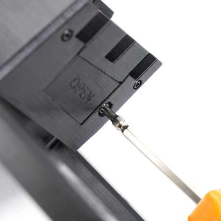 A screwdriver is being used to unscrew a small screw on a black device, with the word OPEN engraved nearby.