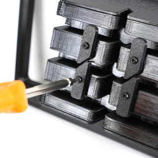 Close-up of a screwdriver adjusting a black mechanical device with multiple rectangular components.