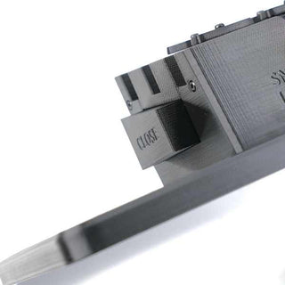 Close-up of a 3D-printed object with a rectangular extension labeled CLOSE, featuring intricate textures and a flat base.