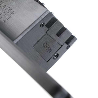 Close-up of a black plastic device with a rectangular section labeled NEED and an OPEN compartment, featuring screws and textured surfaces.