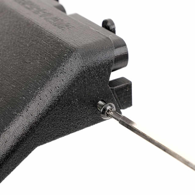 A close-up of a black 3D-printed object with a small metal screw securing a thin metal rod at the end.