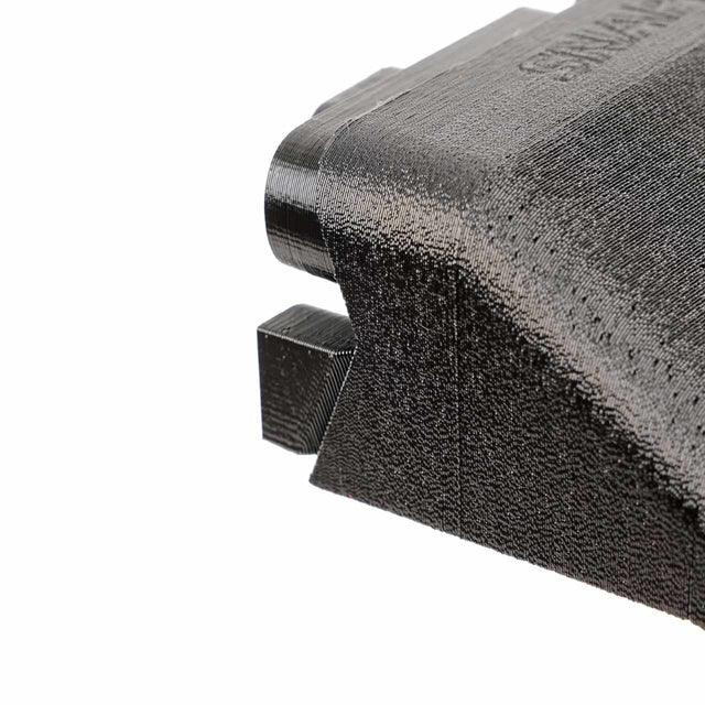 Close-up of a black 3D-printed plastic object with a textured surface, featuring angular and rectangular shapes.