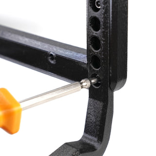 A screwdriver with an orange handle is being used to tighten a screw into a black metal frame with multiple holes.