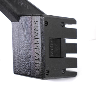 Close-up of a black 3D-printed plastic component labeled SNAPPLATE, featuring a rectangular button with OPEN text and slotted openings on one side.