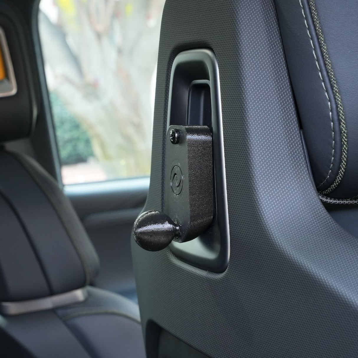 Close-up of the EveryAmp Back Seat Tablet/Phone Mount Anchor, seamlessly integrated into the black leather seat back of a Rivian R1T or R1S—perfect for attaching accessories or a 3D-printed ball mount.