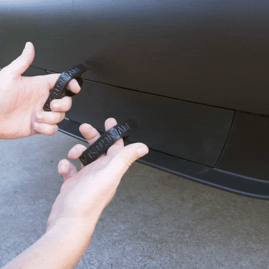 Hands attaching a magnetic cover to a cars charging port, aligning it into place.