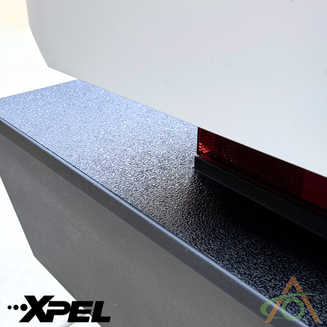 Close-up of a rear bumper with a rough texture, displaying the Abstract Ocean logo in the bottom left corner, showcasing the impressive Ultra-Tough Xpel Armor Rear Bumper Protection for Cybertruck.