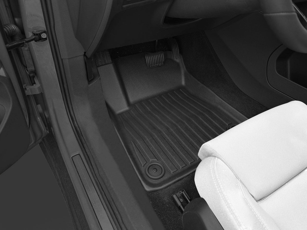 The drivers footwell of the Polestar 2 is equipped with LinerX Floor Mats, offering durable Thermoplastic Elastomer protection and style around the brake and accelerator pedals, along with a glimpse of a white seat, enhancing the driving experience from 2021 to 2025.