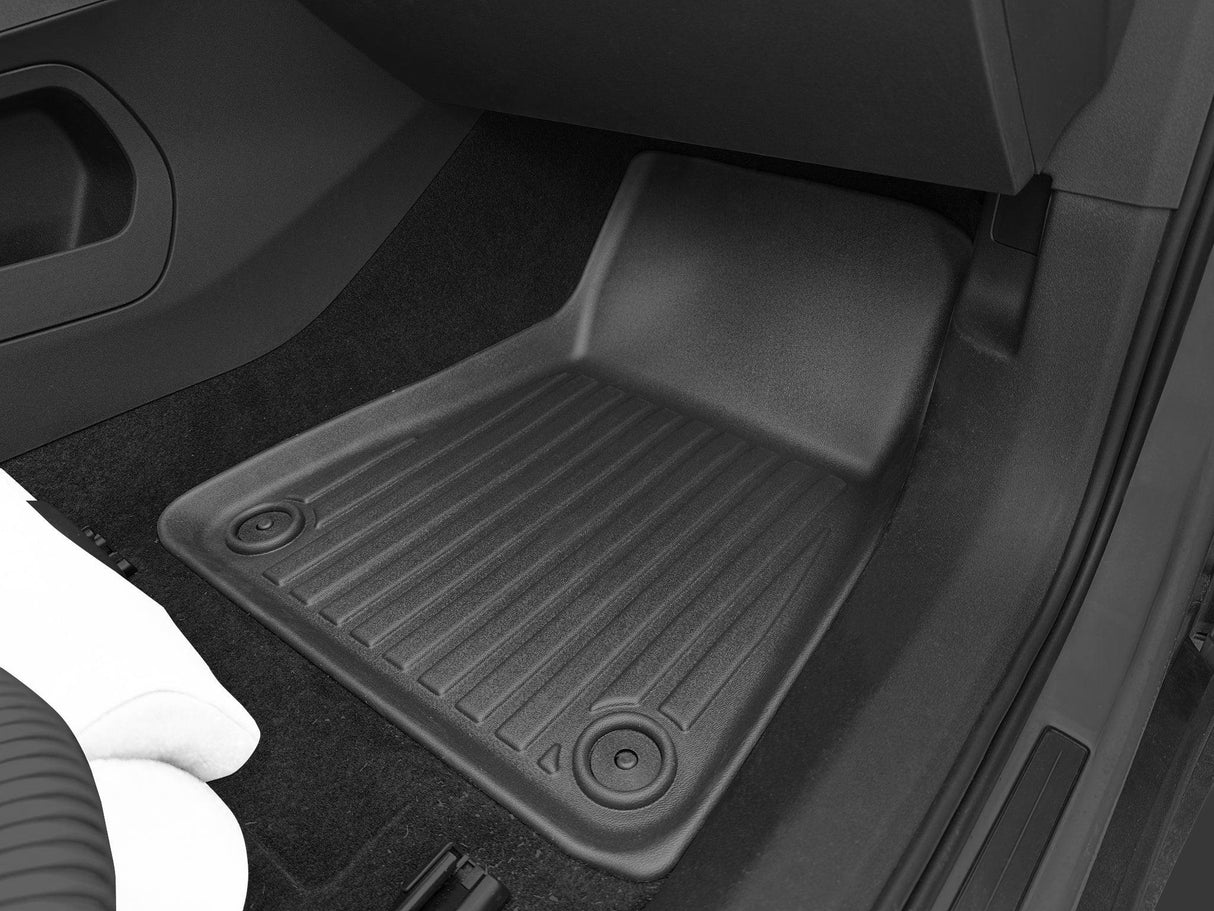 The LinerX Floor Mats for 2021-2025 Polestar 2 enhance the vehicles interior with durable black rubber that blends seamlessly with black carpet and white fabric on the left side, making them a stylish accessory.