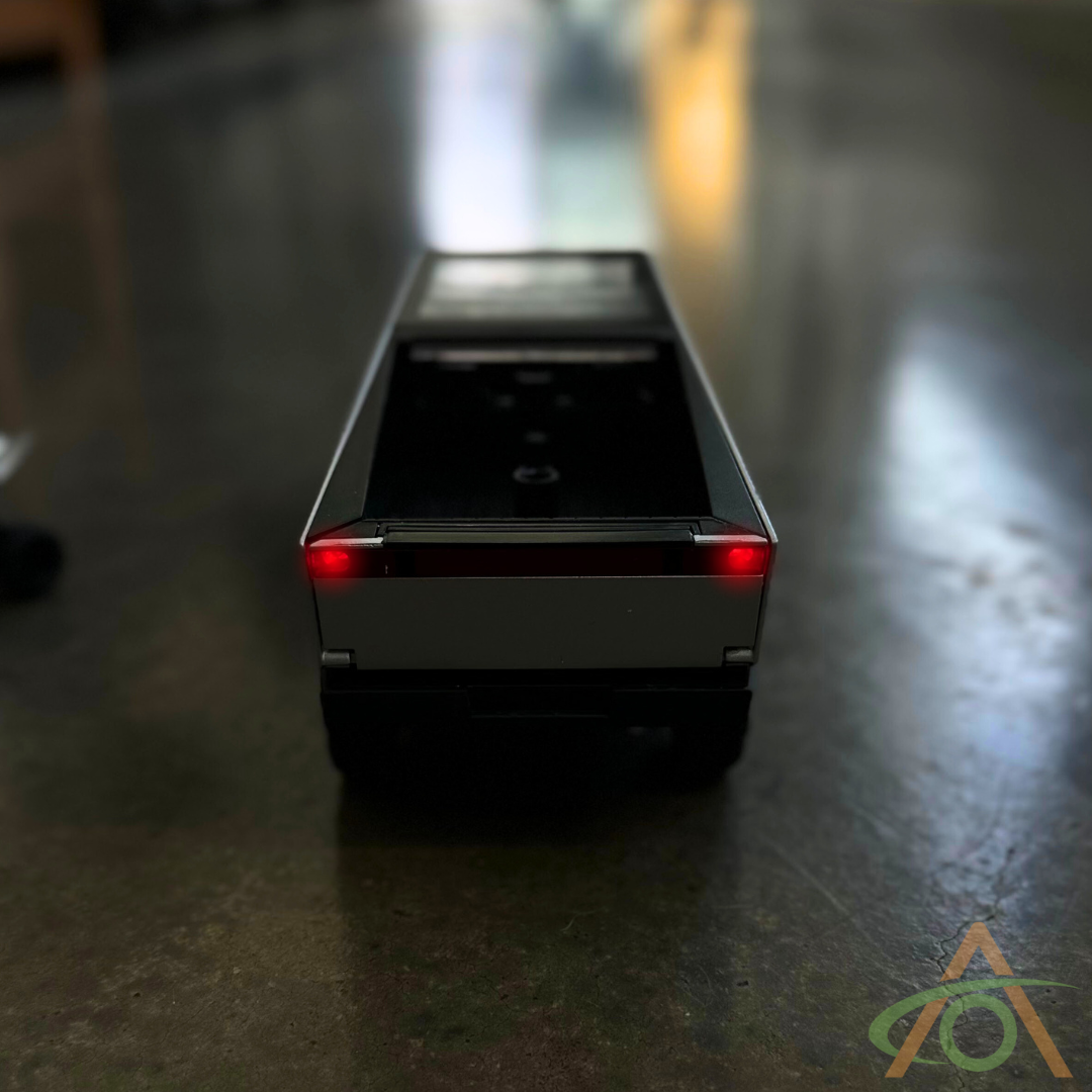 A 1:24 scale Cybertruck and Cyberquad diecast from Abstract Ocean, featuring glowing red taillights on a reflective surface, is ready for its next adventure.