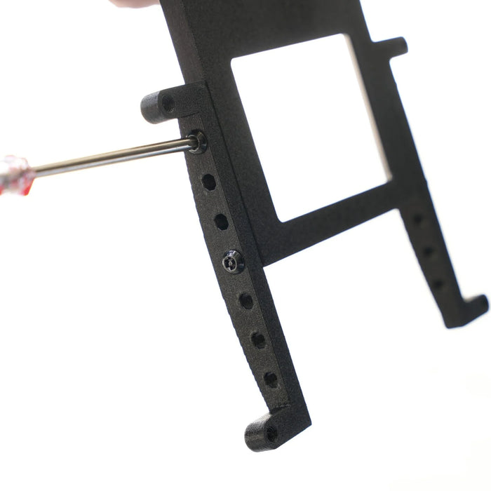 A hand uses a screwdriver to insert a screw into a black rectangular bracket or frame against a white background.