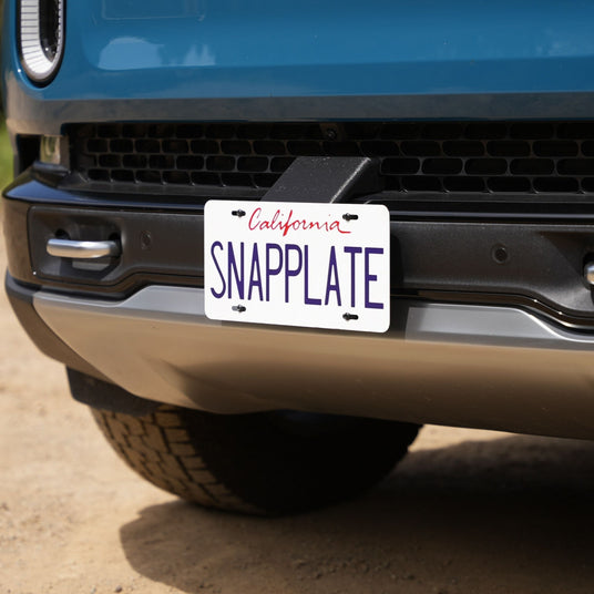Close-up of a cars front bumper featuring a California license plate with the text SNAPPLATE.