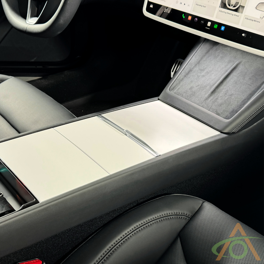 Close-up of a modern car interior showcasing the Abstract Ocean Center Console Vinyl Wrap for Refreshed Model 3 & Y, touchscreen display, and front seats with black and gray upholstery.