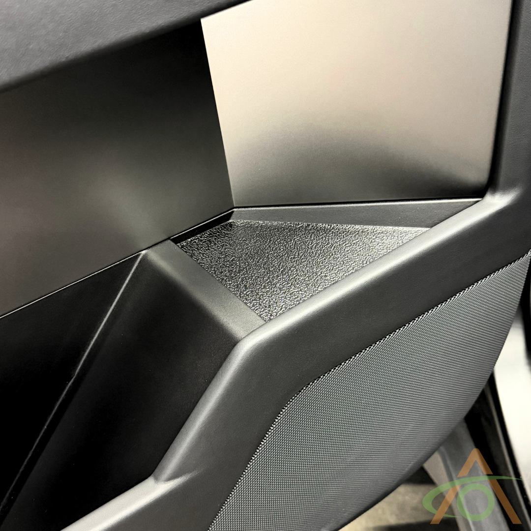 Close-up of a modern chair with a textured black seat and angled backrest, featuring gray mesh panels that evoke the sleek design of Abstract Oceans Xpel Armor Door Inserts for Cybertruck, all set against a neutral background.