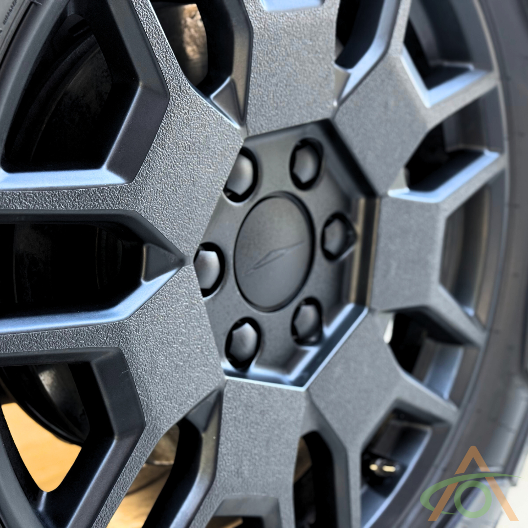 Close-up of an Abstract Ocean Xpel Armor wheel decal for Cybertruck, featuring a black textured hexagonal design with a center logo, ideal for all-terrain adventures.