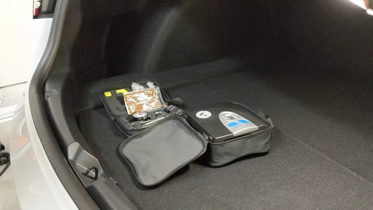 Car trunk with a compact tire repair kit and air compressor neatly placed inside, ready for emergency use.