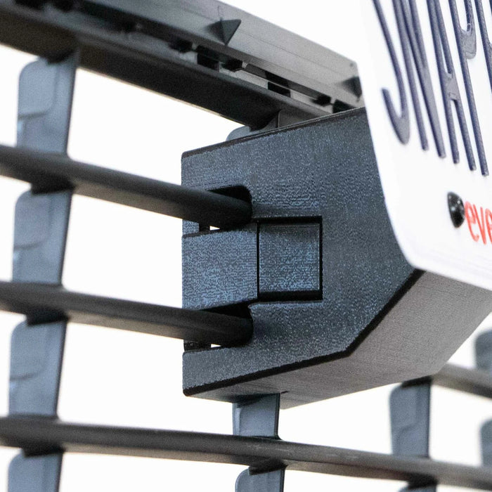 Close-up of a rack with black metal bars and a mounted sign. The sign is partially visible with bold text. The rack has a textured connector securing the bars.
