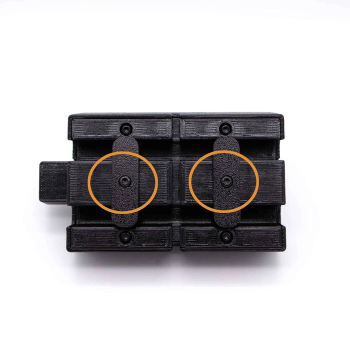 A black mechanical component with two orange circles highlighting specific areas on a white background.