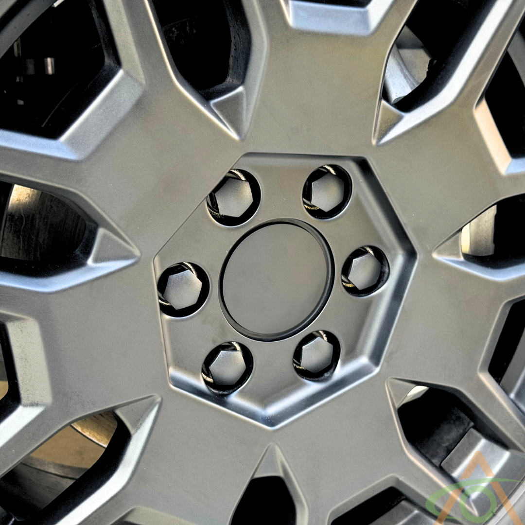 Close-up of an Abstract Ocean Wheel Center Cap & Lug Nut Cover for Cybertruck in black, featuring a hexagonal pattern with a central circle and six lug nut holes.