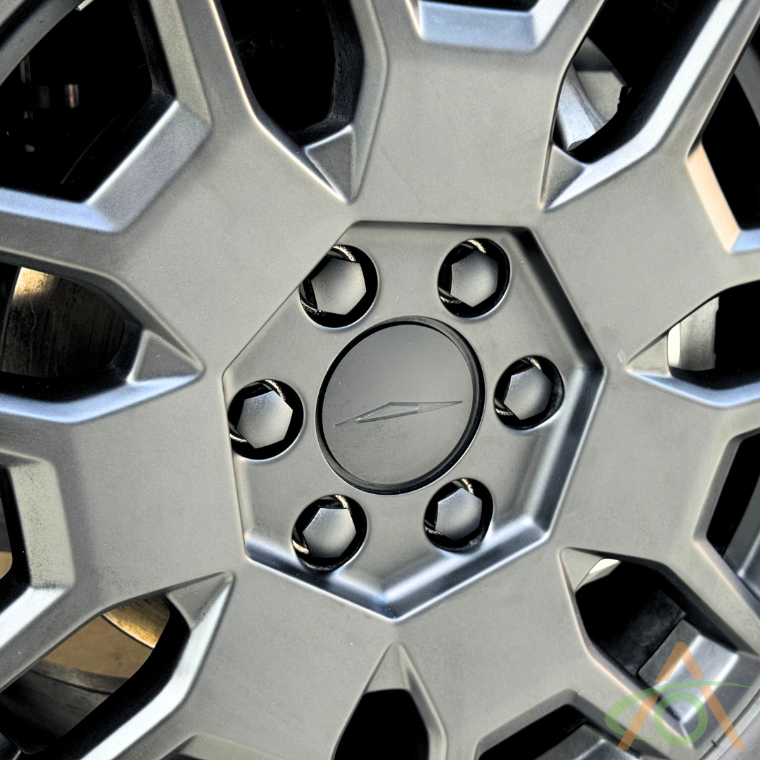 A close-up of Abstract Oceans Cybertruck Wheel Center Caps and sleek Lug Nut Covers showcases a hexagonal central design and six surrounding bolt holes.
